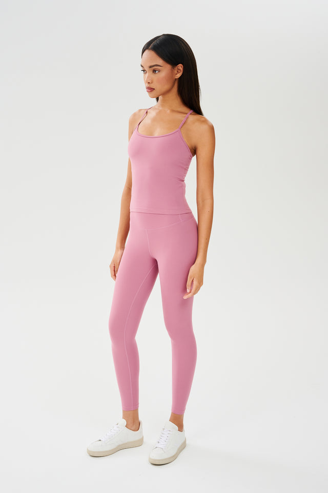 Full side view of girl wearing highwasited pink leggings with pink tank top and white shoes