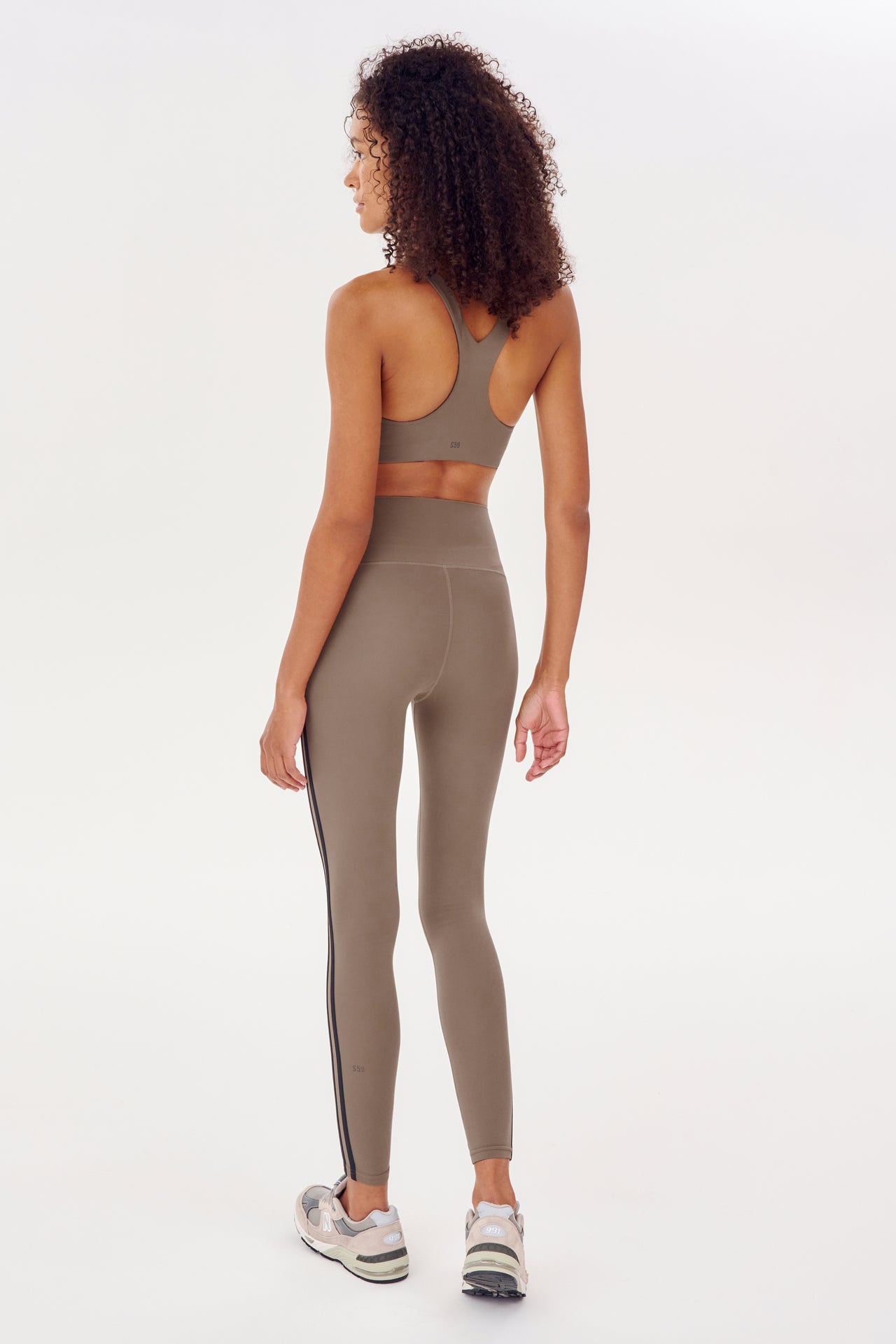The back view of a woman in an Ella Airweight Bra - Lentil/Black from SPLITS59 collection, racer back bra, and leggings.