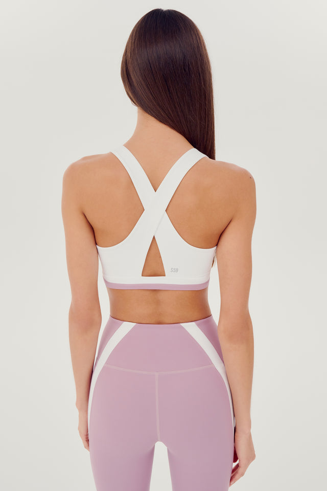 The back view of a woman wearing a Miles Rigor Bra in Blush/White by SPLITS59 designed for style and support during workouts.