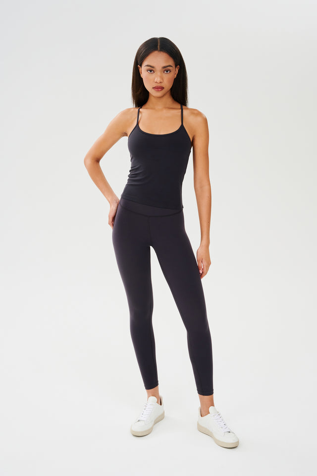 Full front view of girl wearing black spaghetti strap tank top with black leggings and white shoes