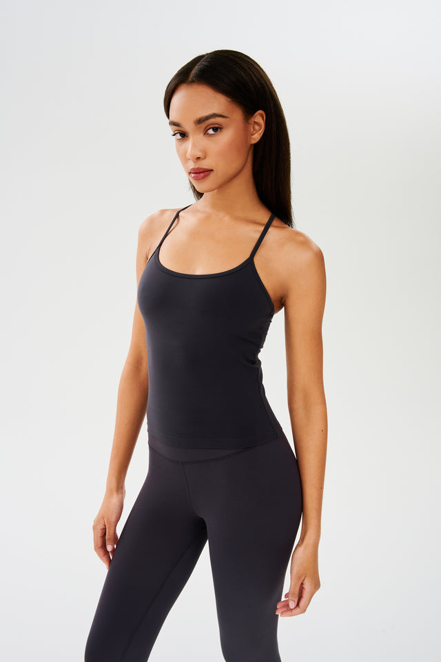Side view of girl wearing black spaghetti strap tank top with black leggings 