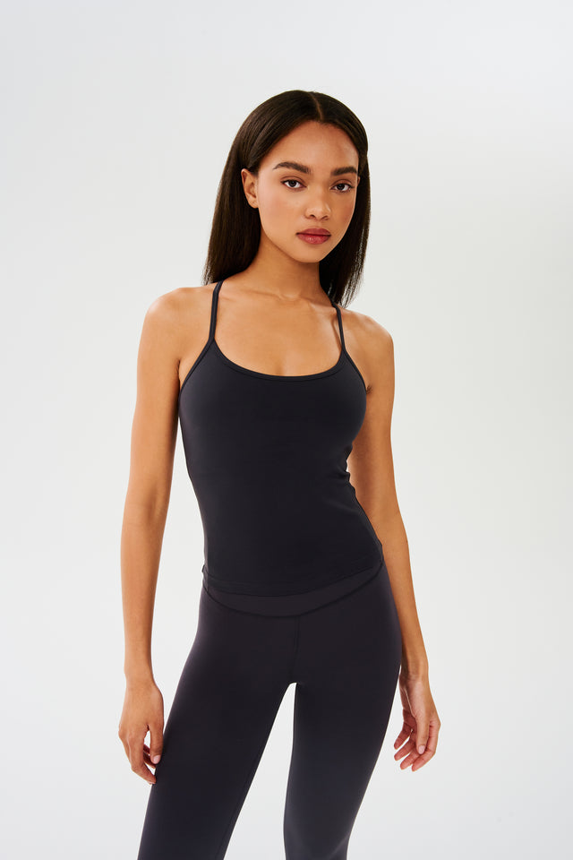 Front view of girl wearing black spaghetti strap tank top with black leggings