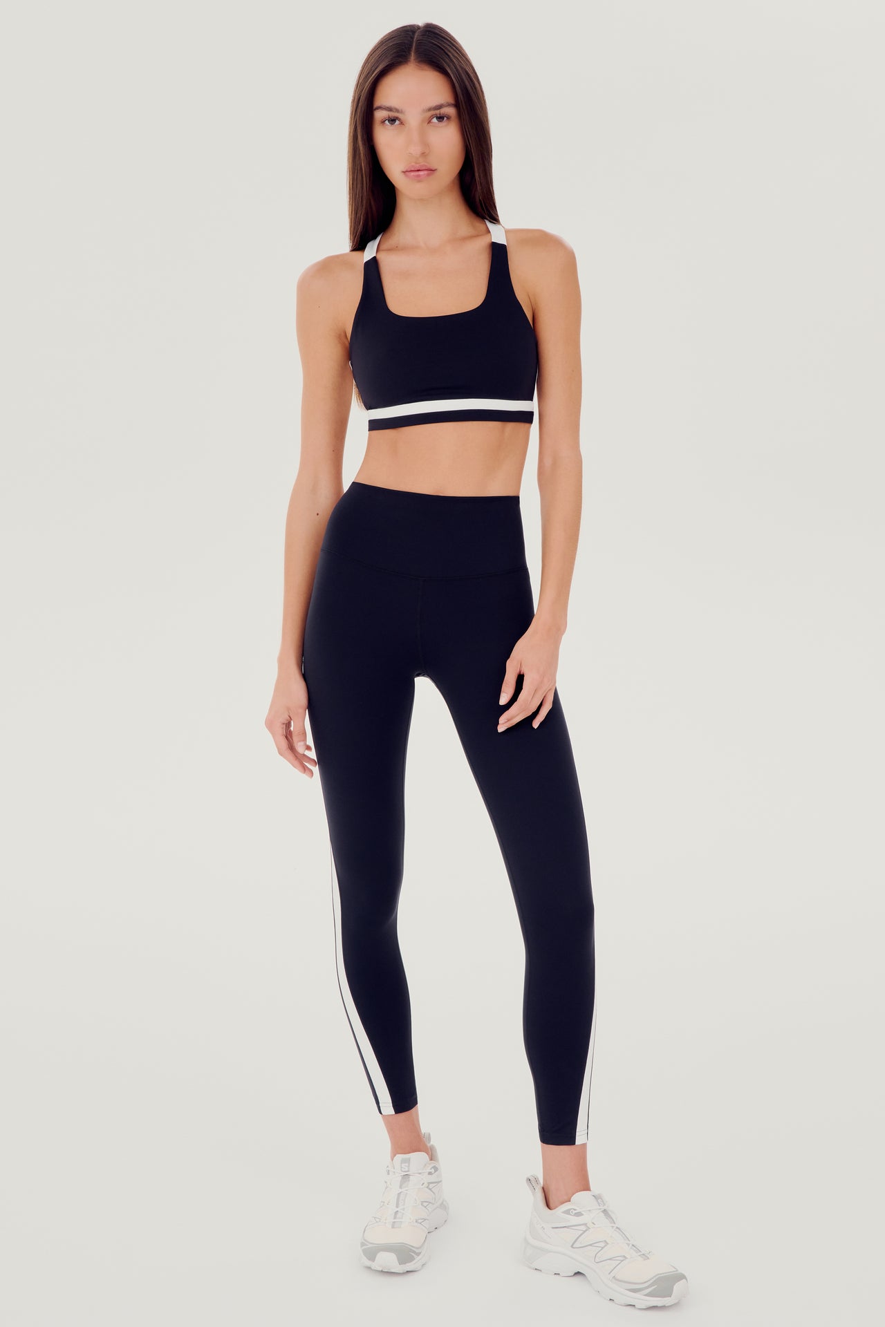 A woman wearing a SPLITS59 Miles Rigor Bra in Black/White designed for style and support, and leggings suitable for workouts.