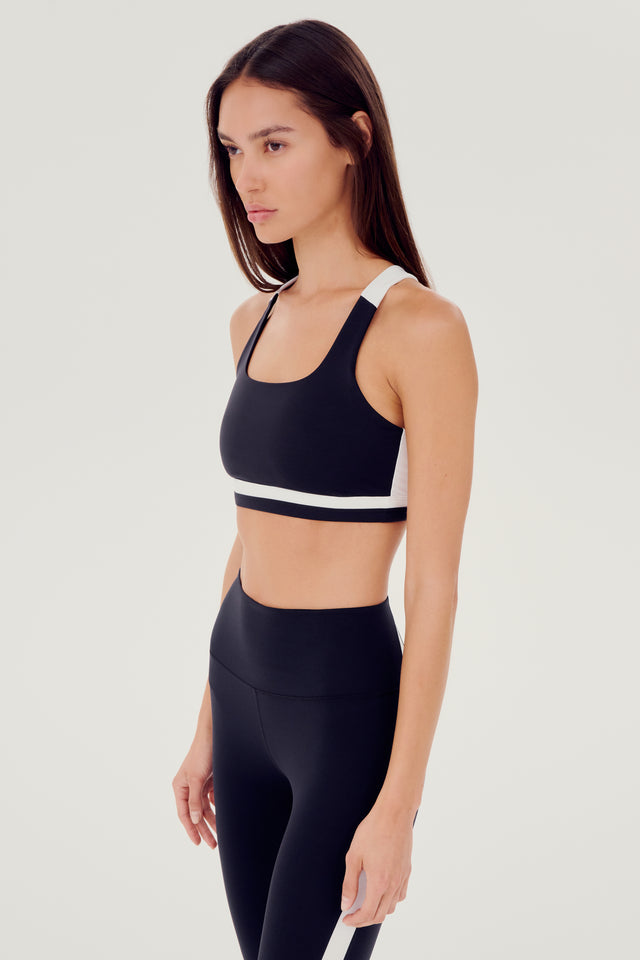 A woman wearing a SPLITS59 Miles Rigor Bra in Black/White designed for support during workouts.