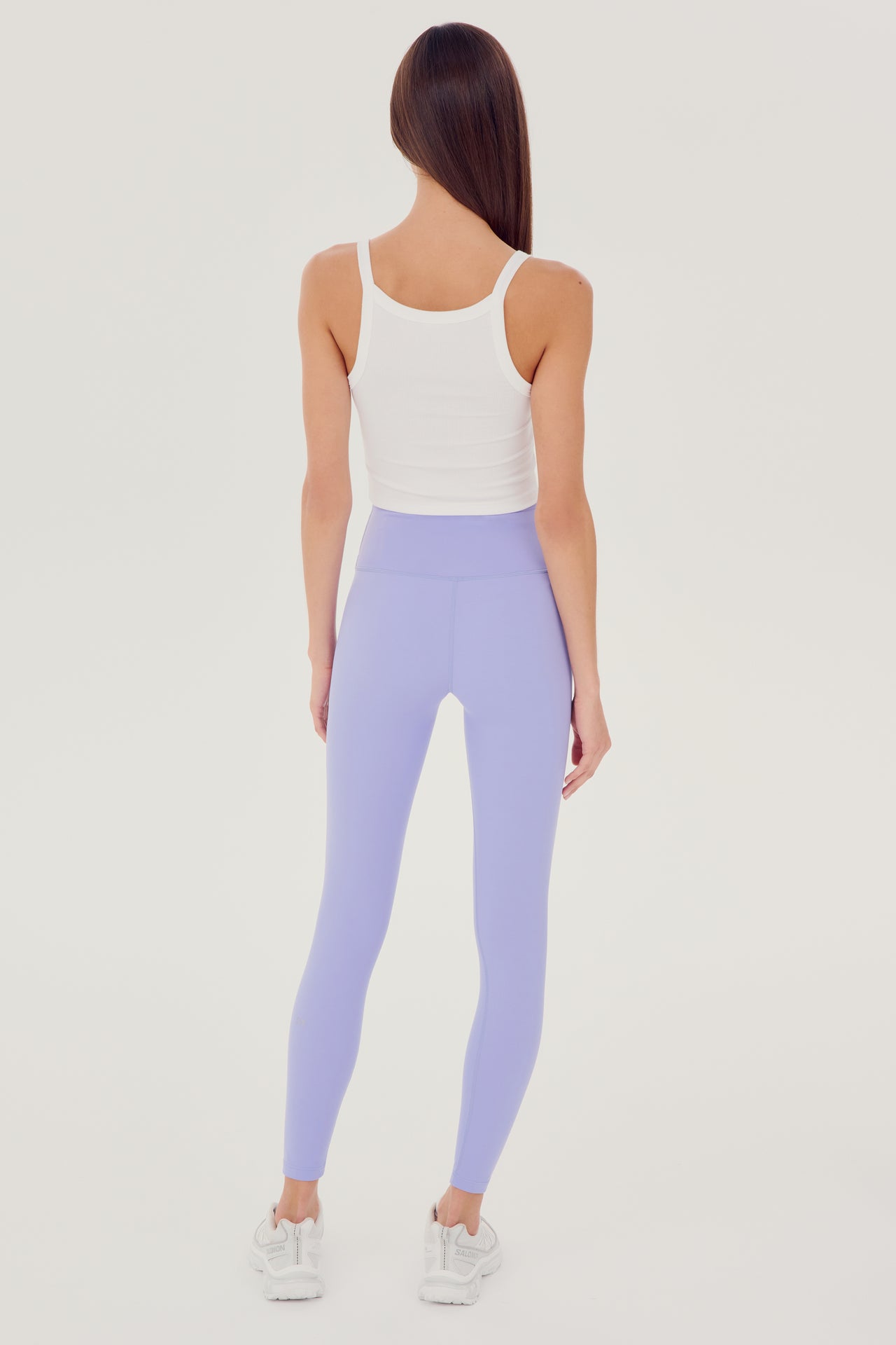 Full back view of girl wearing white ribbed square neck cropped tank top with light purple leggings and white shoes