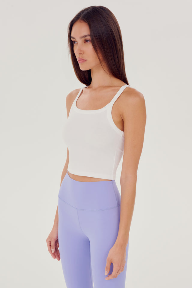 Side view of girl wearing white ribbed square neck cropped tank top with light purple leggings 