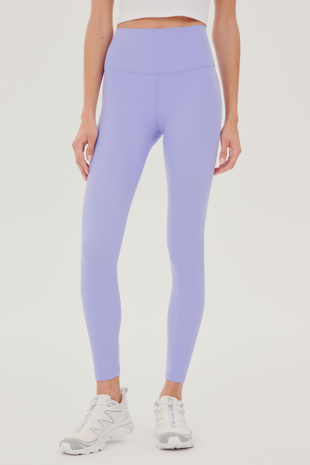 Front view of model wearing light purple high waist  leggings with white cropped tank and white shoes