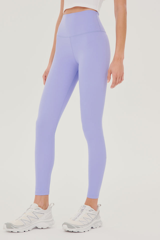 Front side view of model wearing light purple high waist leggings with white cropped tank and white shoes
