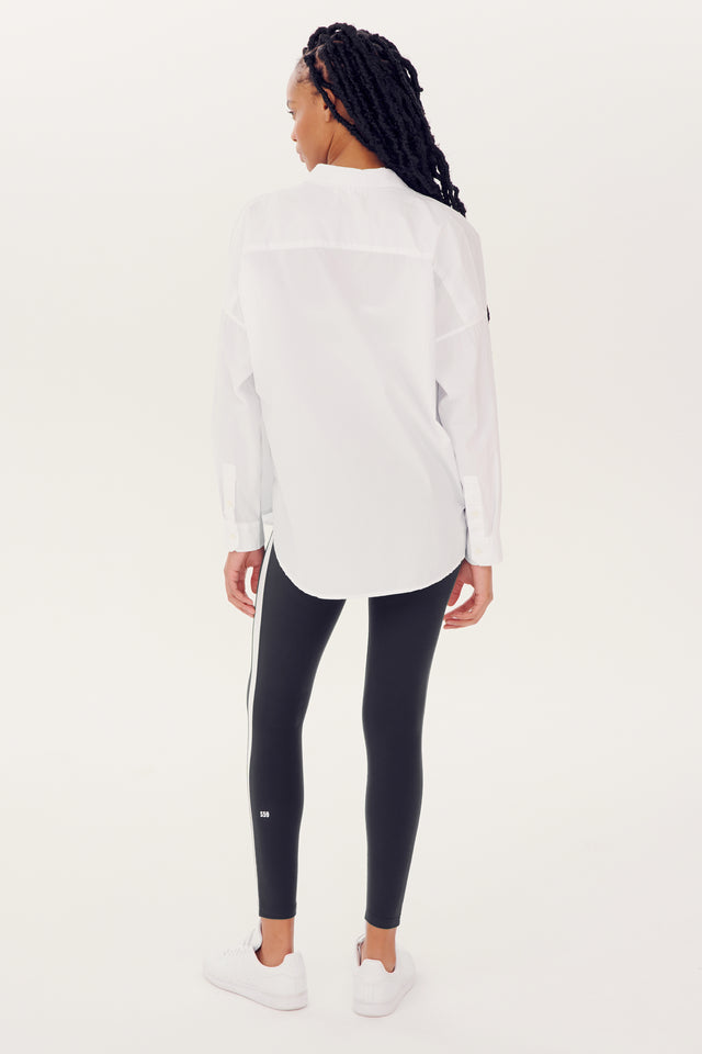 Woman standing in profile wearing an oversized Alex Mill x Splits59 Jo Shirt - White and black leggings.