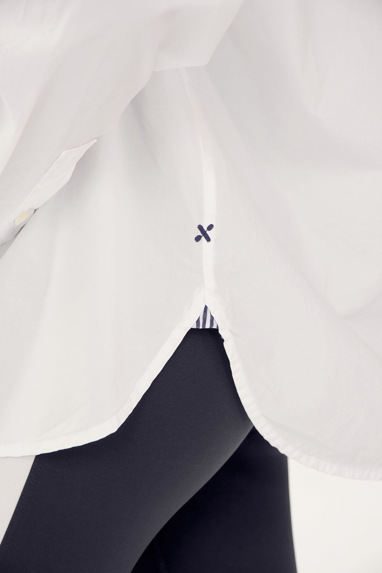 A close-up view of a person wearing an oversized Alex Mill x Splits59 Jo Shirt - White with a small black detail and black pants.
