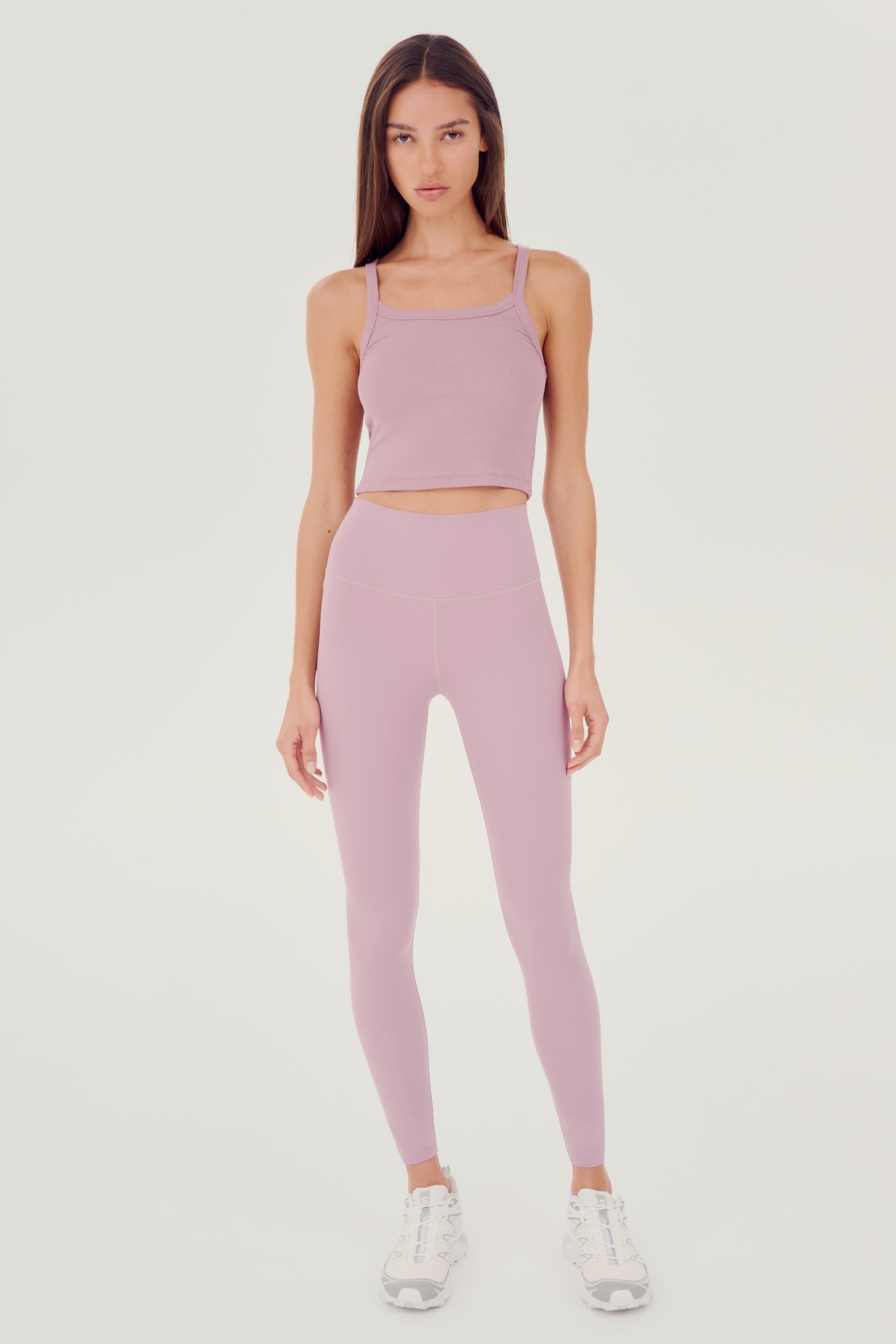 Full front view of girl wearing light pink ribbed square neck cropped tank top with light pink leggings and white shoes 