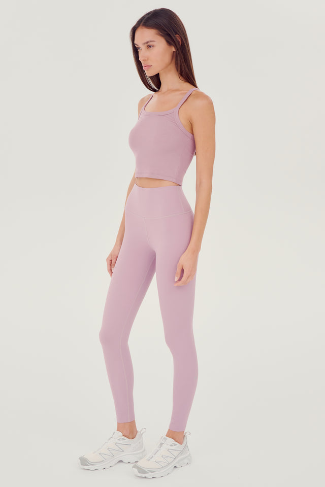 Full side view of girl wearing light pink ribbed square neck cropped tank top with light pink leggings and white shoes 
