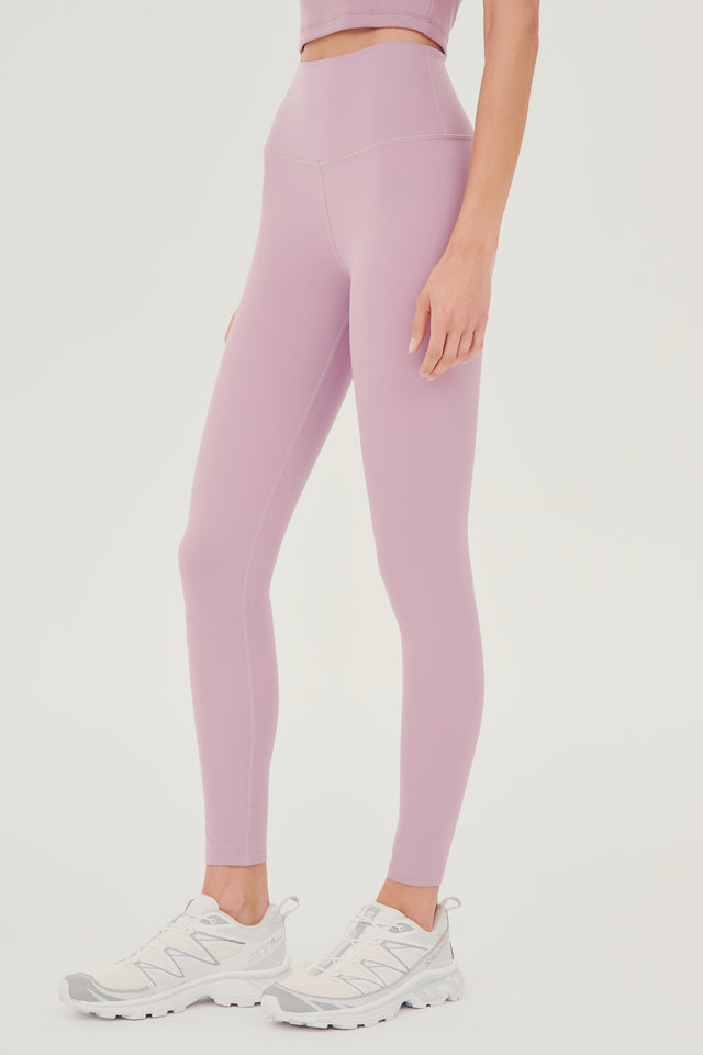 Front side view of model wearing light pink high waist legging paired with white shoes