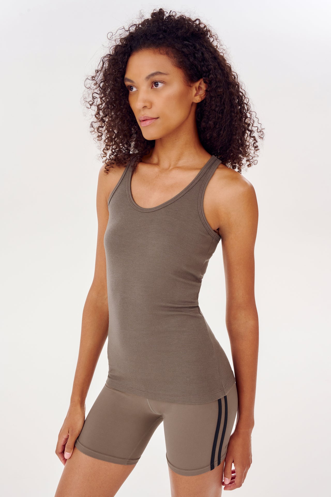 A woman wearing a SPLITS59 Ashby Rib Tank in Lentil and shorts.