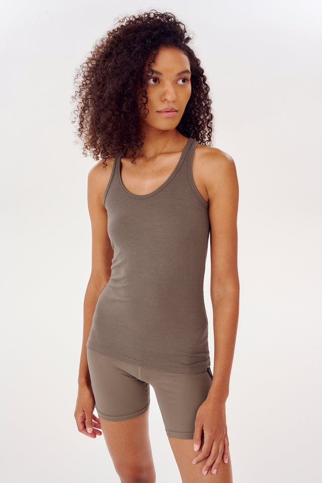 A woman wearing an Ashby Rib Tank in Lentil by SPLITS59 and shorts.