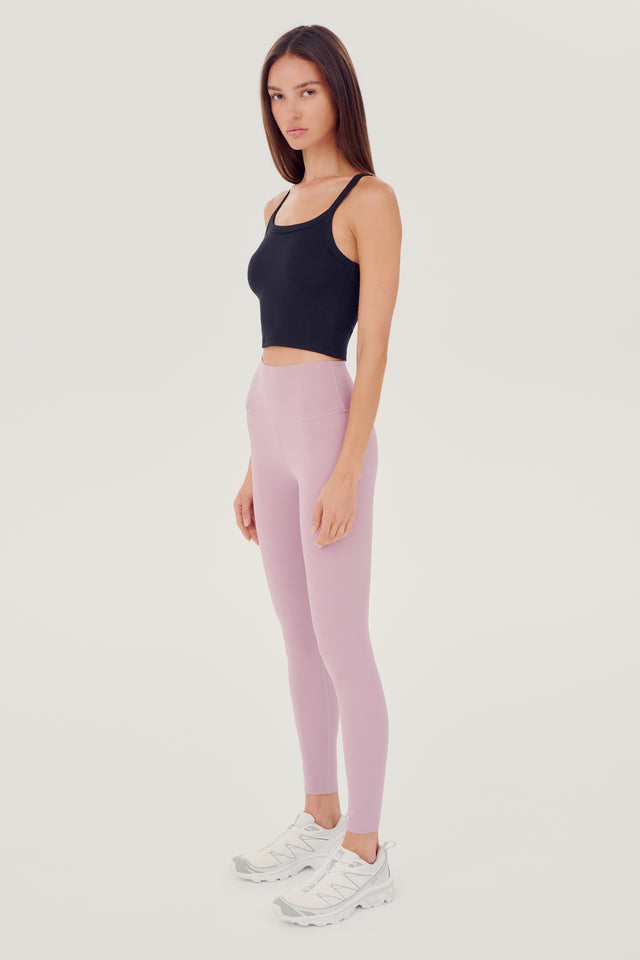 Full side view of girl wearing black ribbed square neck cropped tank top with light pink leggings and white shoes