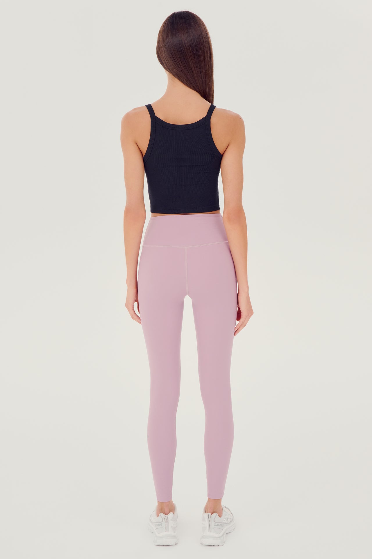 Full back view of girl wearing black ribbed square neck cropped tank top with light pink leggings and white shoes