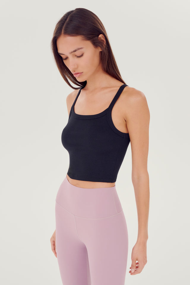 Side view of girl wearing black ribbed square neck cropped tank top with light pink leggings 