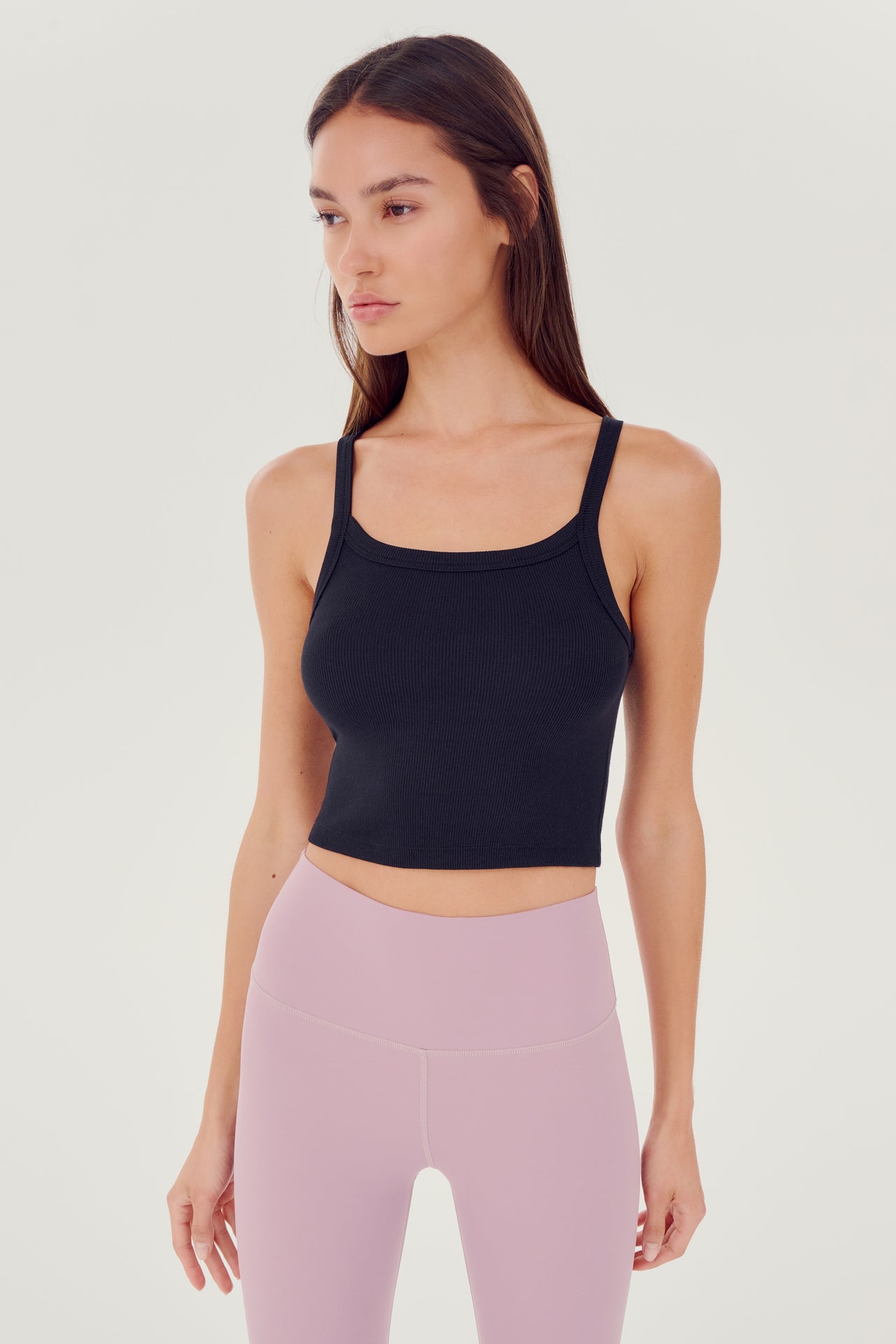 Front view of girl wearing black ribbed square neck cropped tank top with light pink leggings 