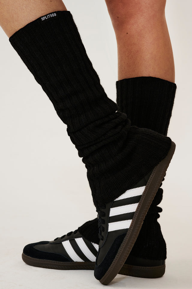 A woman wearing SPLITS59 black leg warmers and a pair of sneakers.