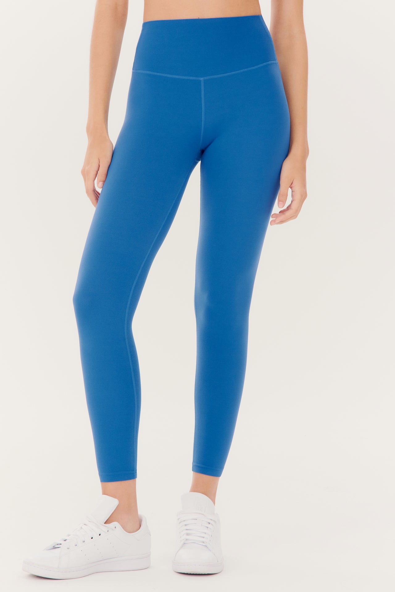 A person wearing Splits59 Airweight High Waist Legging in Stone Blue and white sneakers.