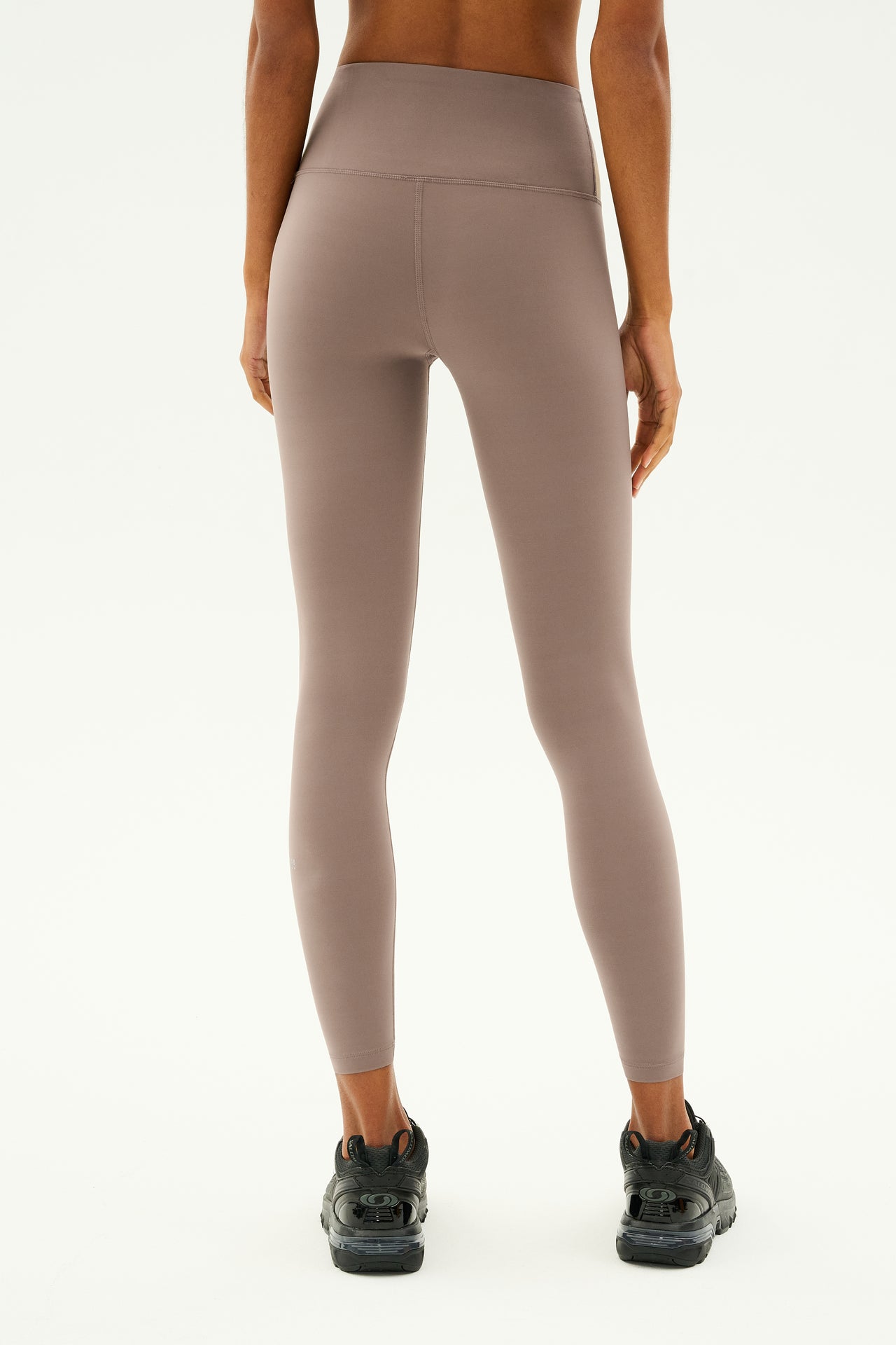 A person wearing the Sprint High Waist Rigor 7/8 - Lentil leggings by SPLITS59 and black sneakers is standing with their back to the camera against a plain background.