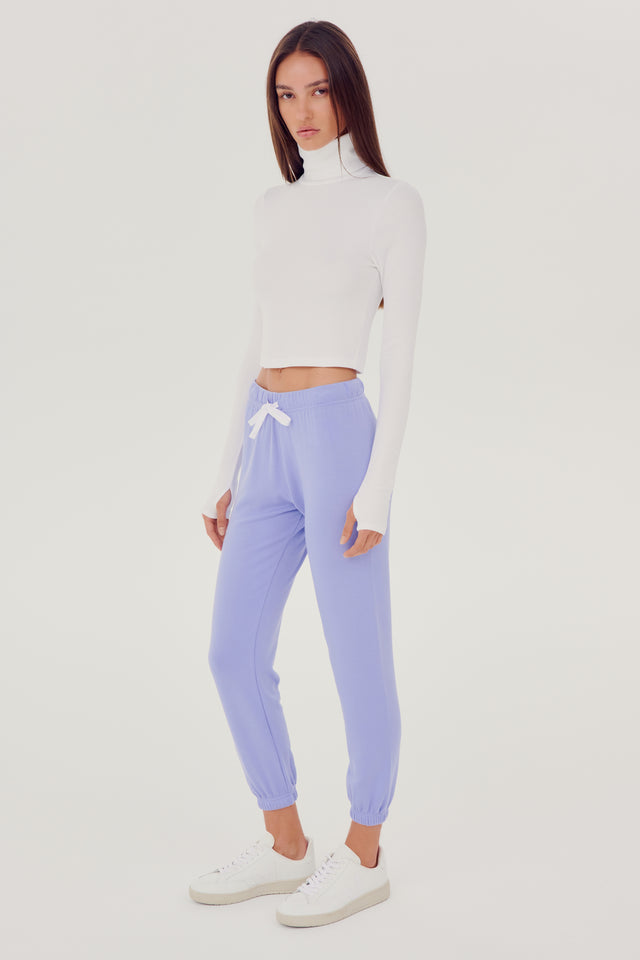 The model is wearing a white SPLITS59 Jackson Rib Cropped Turtleneck and lavender high waist leggings.