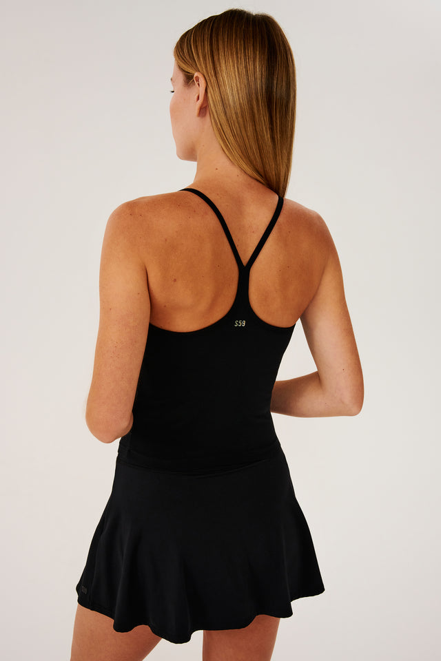 Back view of girl wearing black spaghetti strap tank top with black skirt