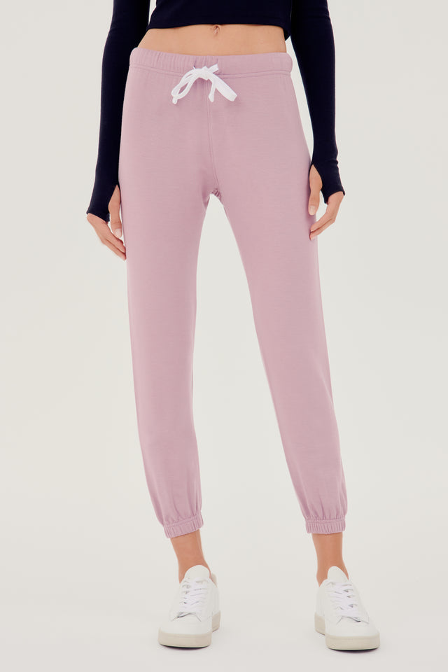 Front view of woman wearing light pink sweatpant jogger with white drawstring and black turtleneck cropped long sleeve paired with white shoes