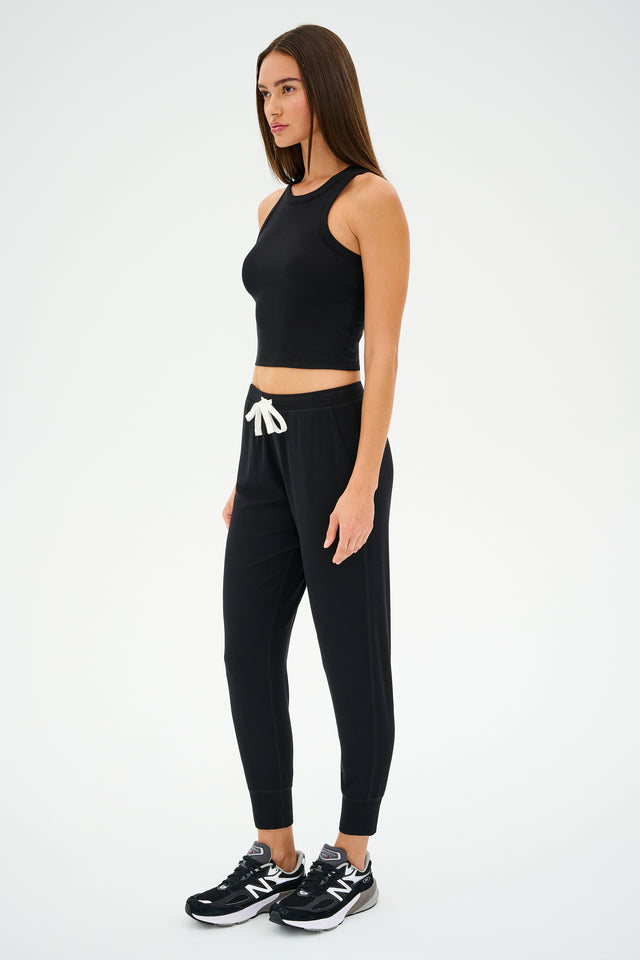 A person wearing a black tank top, Kiki Rib 7/8 Sweatpant by SPLITS59, and sneakers stands against a plain background, embodying the effortless style of MADE IN LOS ANGELES.