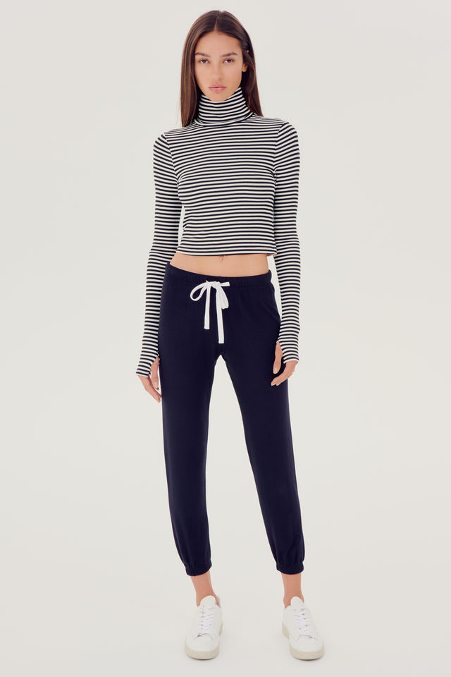 The model is wearing a grey SPLITS59 Jackson Rib Cropped Turtleneck top and black high waist leggings.