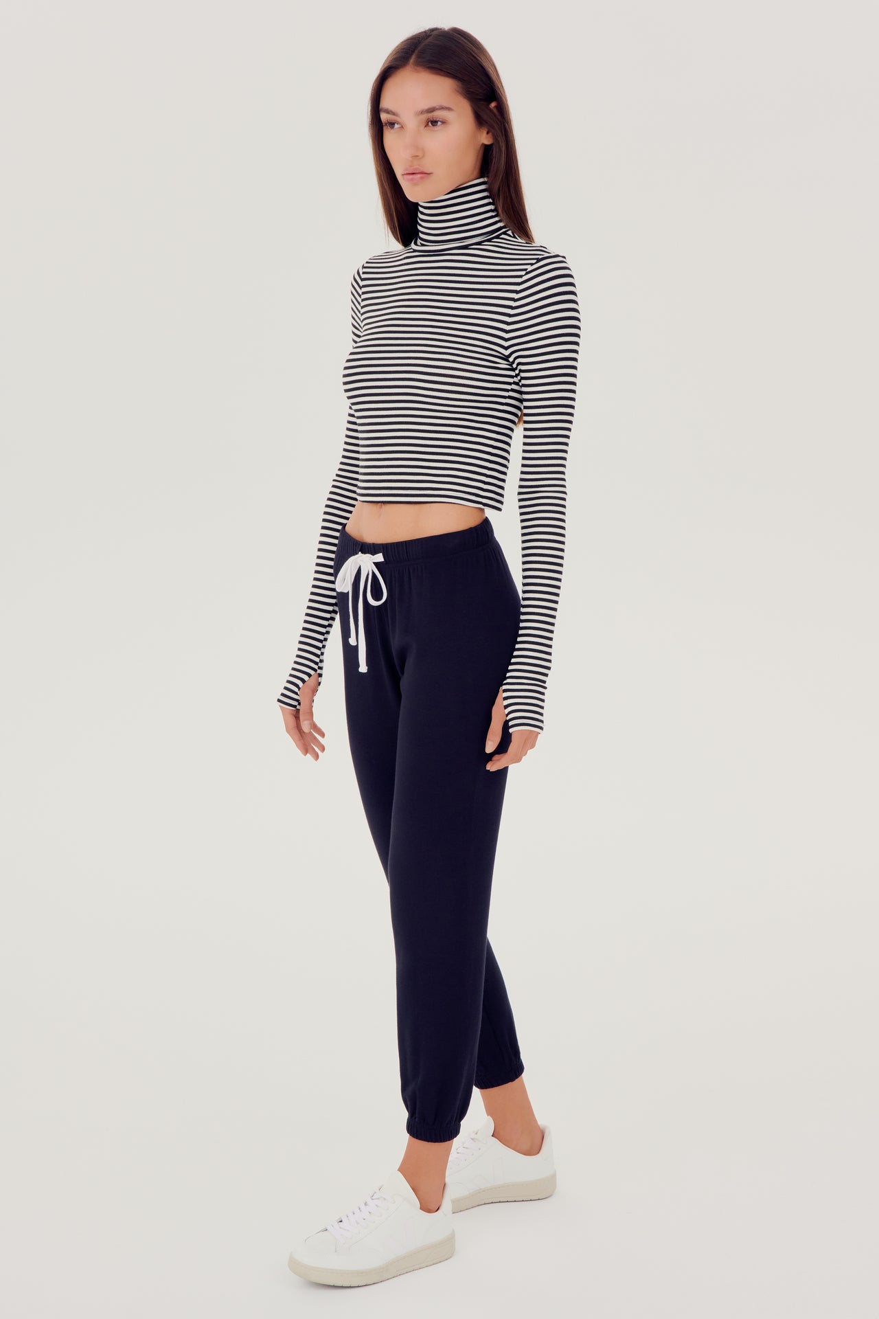 The model is wearing a grey SPLITS59 Jackson Rib Cropped Turtleneck top and high waist black leggings.