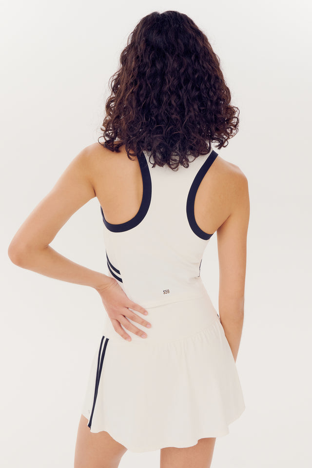 Woman wearing a Splits59 Austin Airweight Crop Polo - White/Indigo sports dress with black trim, viewed from the back.