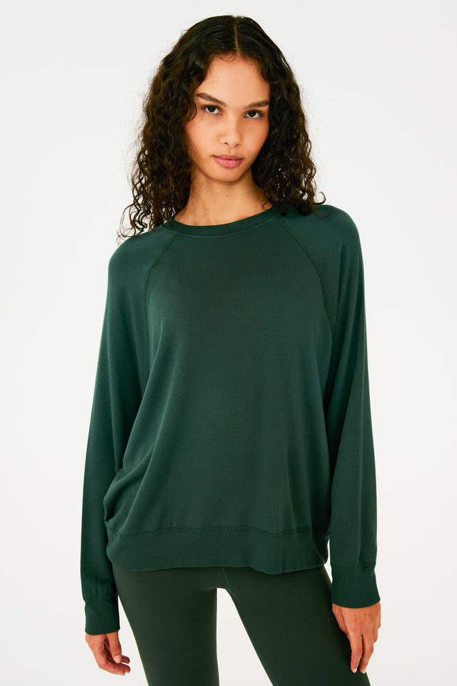 Front view of girl wearing dark green sweatshirt with visible stitching and ribbed hem