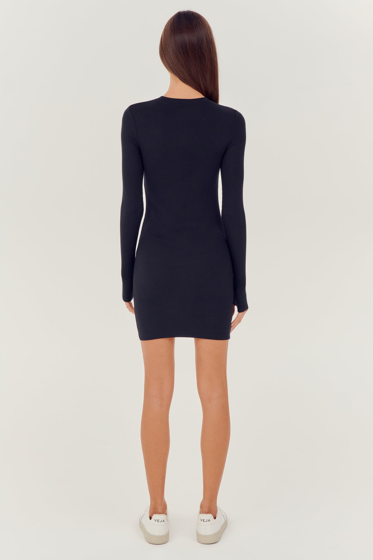 The back view of a woman wearing a SPLITS59 Louise Rib Long Sleeve Dress in Black.