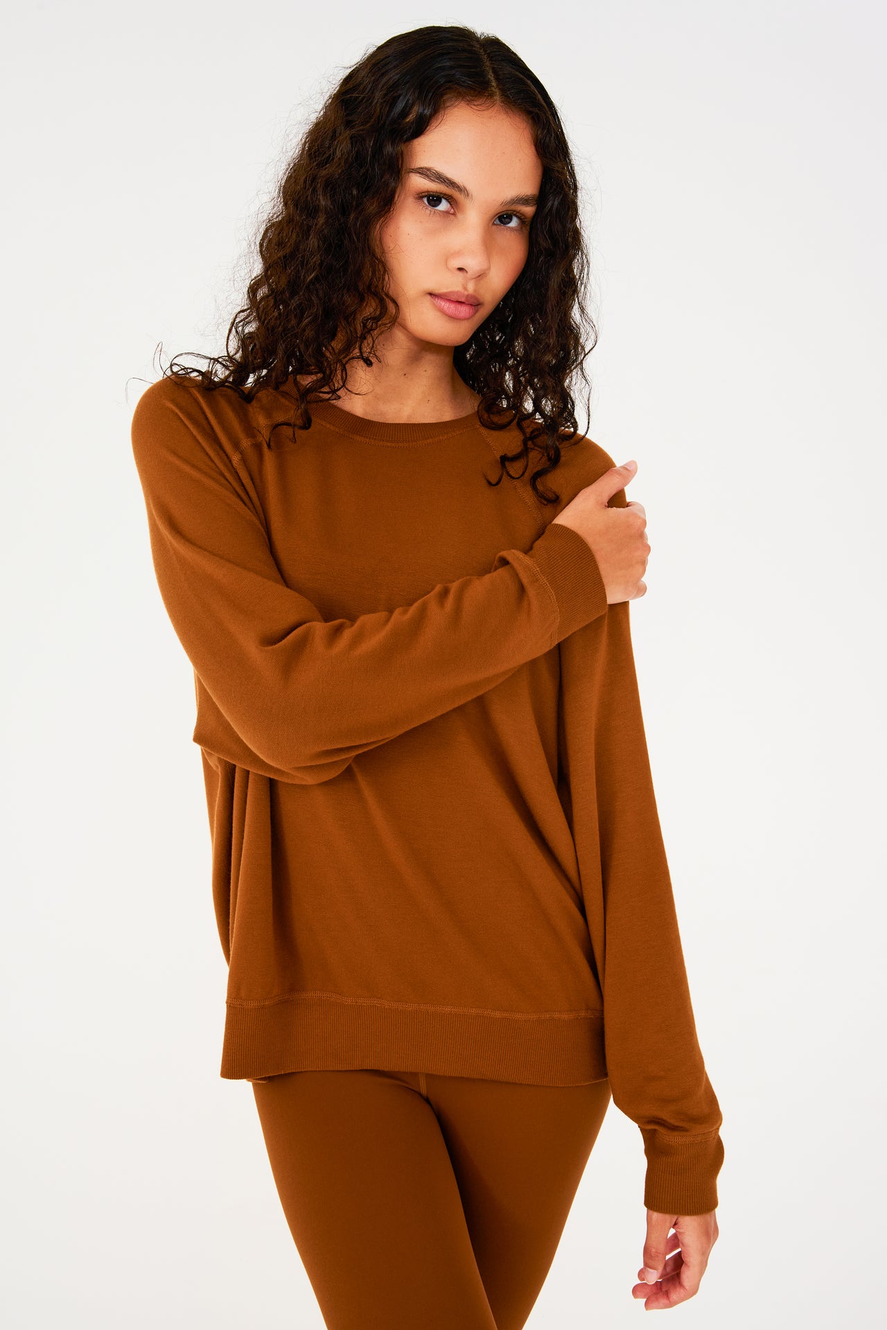 Front view of girl wearing redish brown sweatshirt with visible stitching and ribbed hem