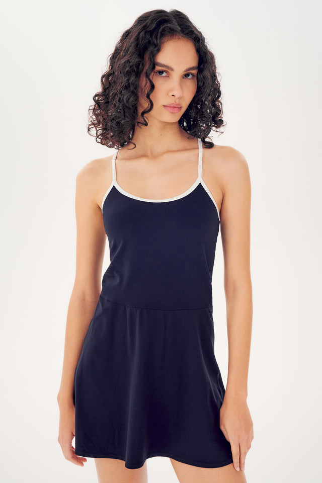 Woman posing in a Simona Airweight Tank Dress by SPLITS59, made of nylon spandex fabric with thin straps against a white background.