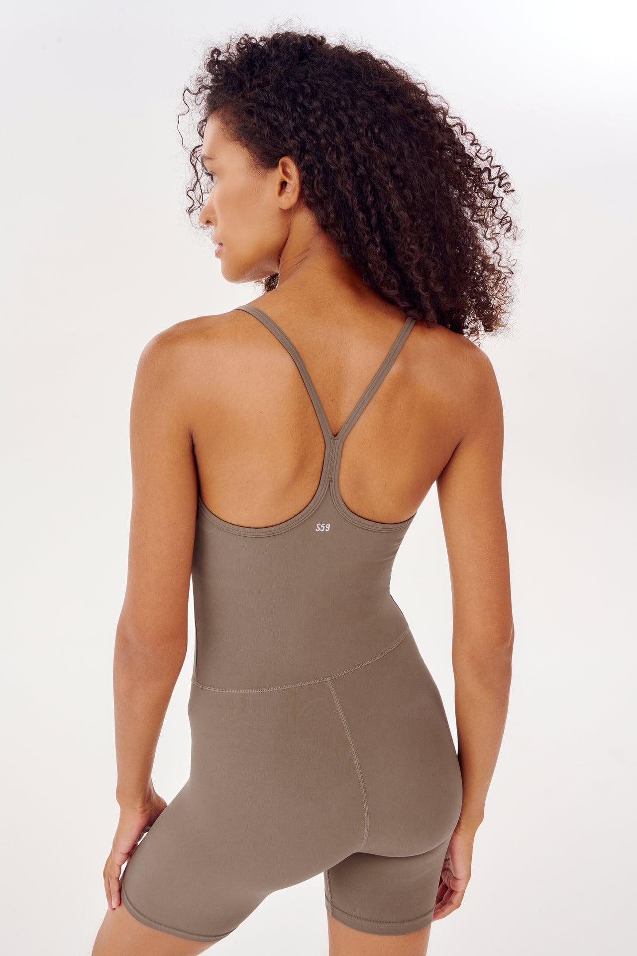 A woman in an Airweight 6” Short Jumpsuit designed for hot yoga by SPLITS59.