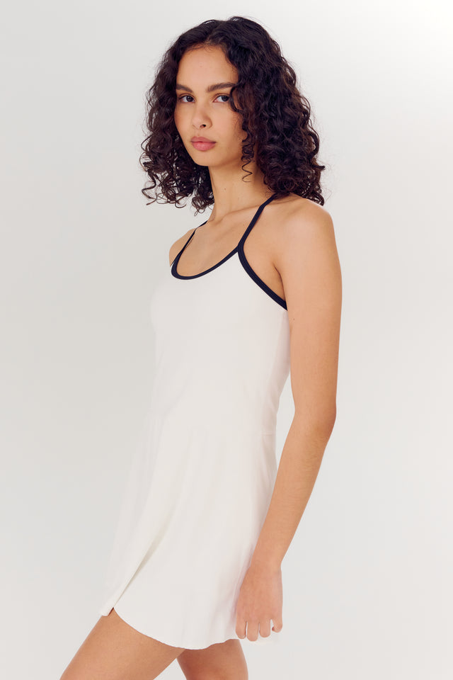 A woman in a SPLITS59 Simona Airweight Tank Dress in White/Indigo with black trim looking to the side.