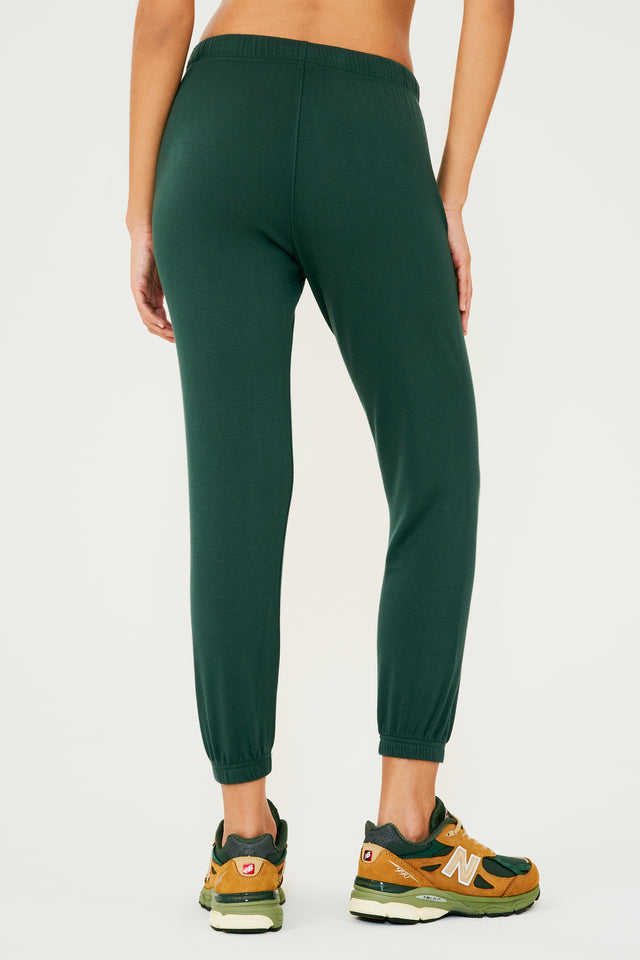 Back view of woman wearing dark green sweatpant jogger paired with dark green, orange and light green shoes