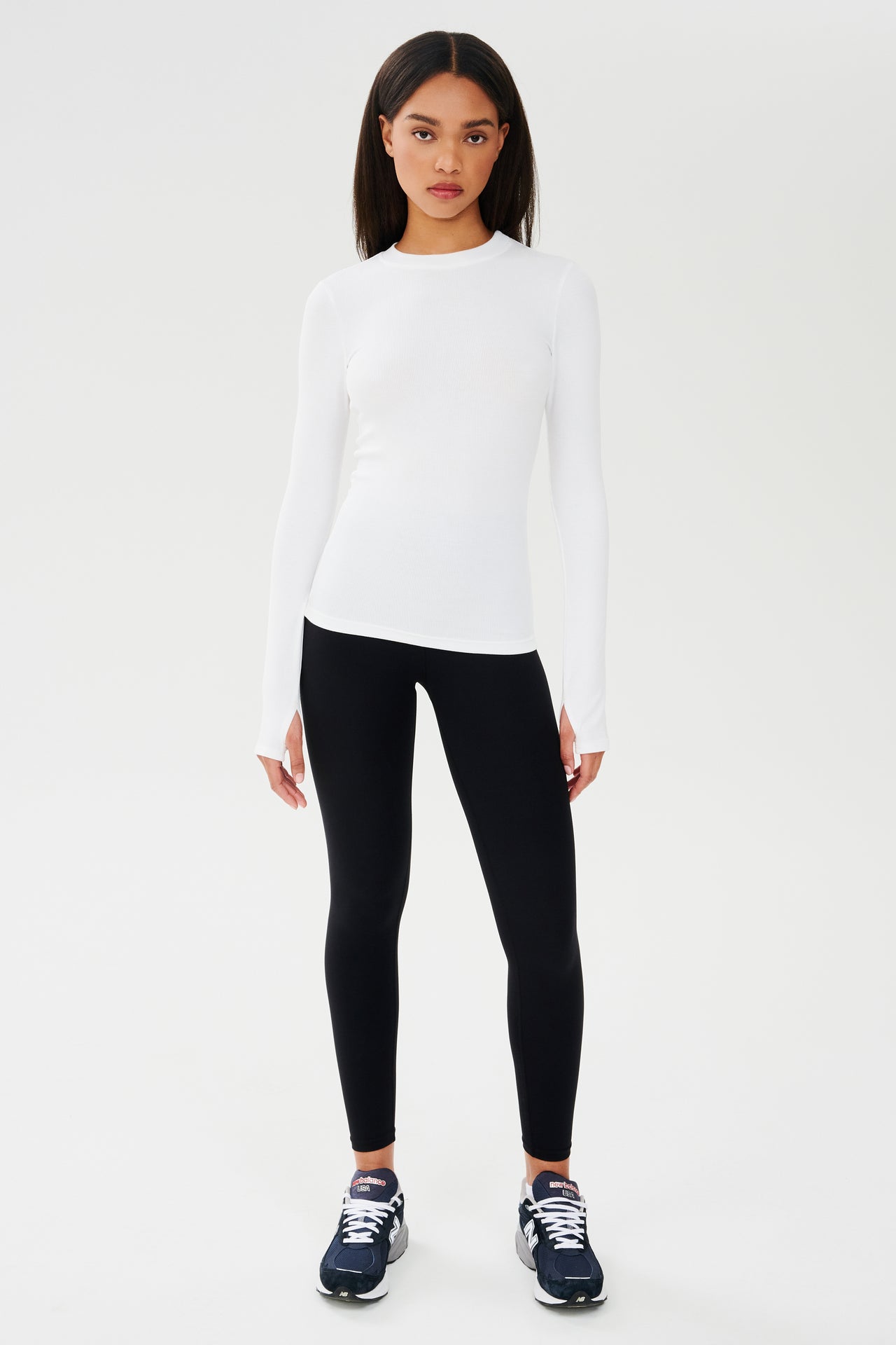 A woman wearing a SPLITS59 Louise Rib Long Sleeve - White shirt and black leggings for yoga.