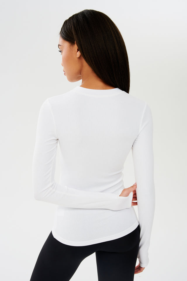 The back view of a woman wearing a SPLITS59 Louise Rib Long Sleeve - White top for yoga.