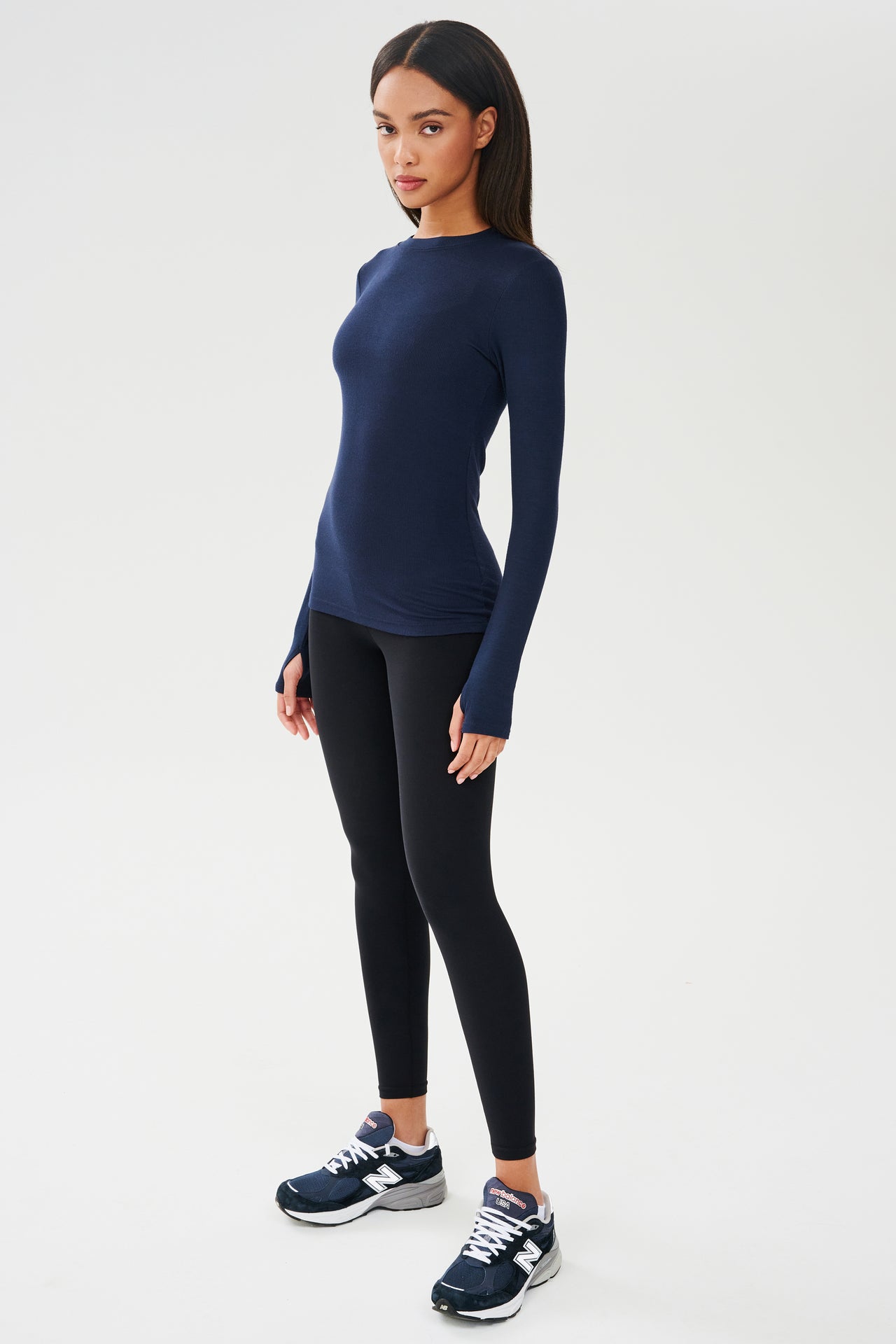 A woman wearing a SPLITS59 Louise Rib Long Sleeve in Indigo and black leggings, ready for her yoga session.