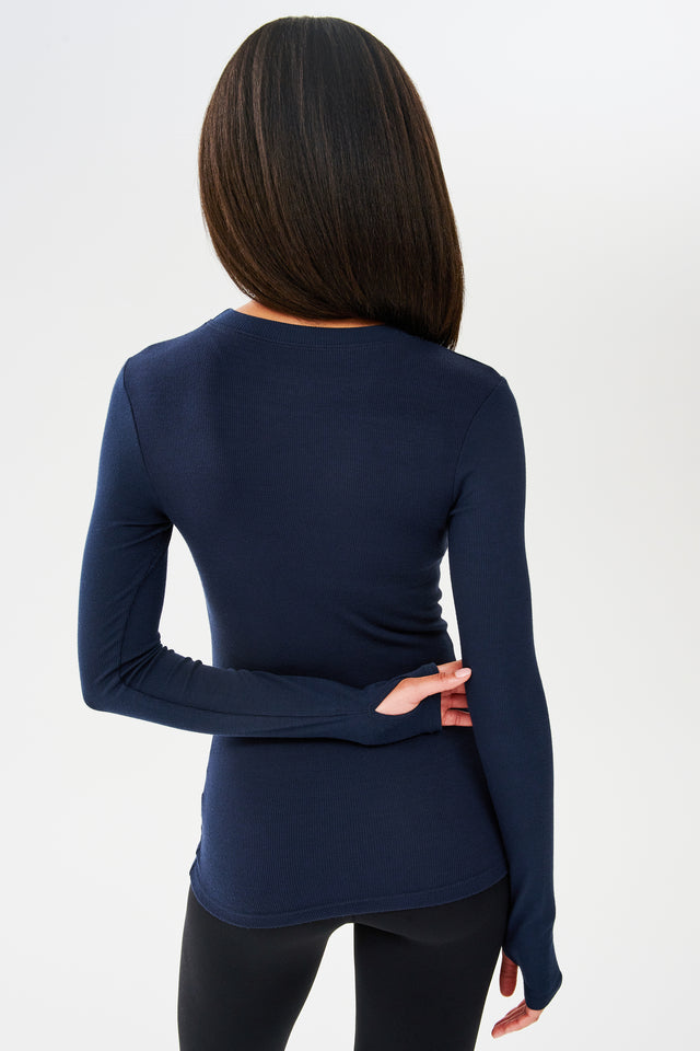 The back view of a woman wearing a SPLITS59 Louise Rib Long Sleeve in Indigo, ideal for yoga.