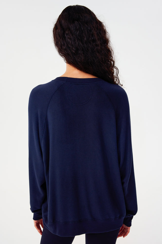 Back view of girl wearing dark blue sweatshirt with visible stitching and ribbed hem
