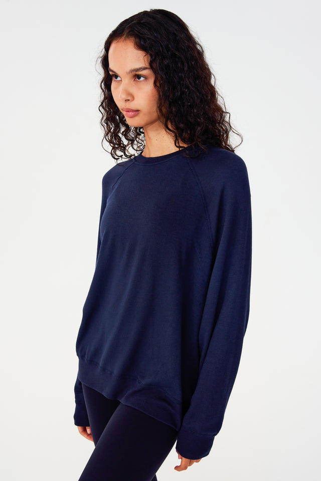 Side view of girl wearing dark blue sweatshirt with visible stitching and ribbed hem