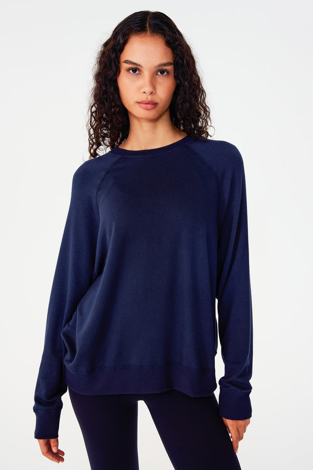 Front view of girl wearing dark blue sweatshirt with visible stitching and ribbed hem