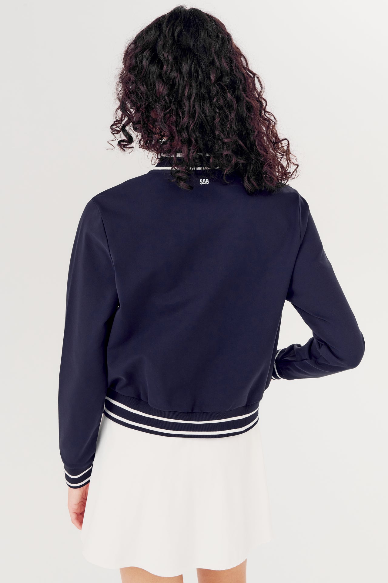 A person seen from behind wearing a SPLITS59 Ever Supplex Jacket in Indigo and white skirt.