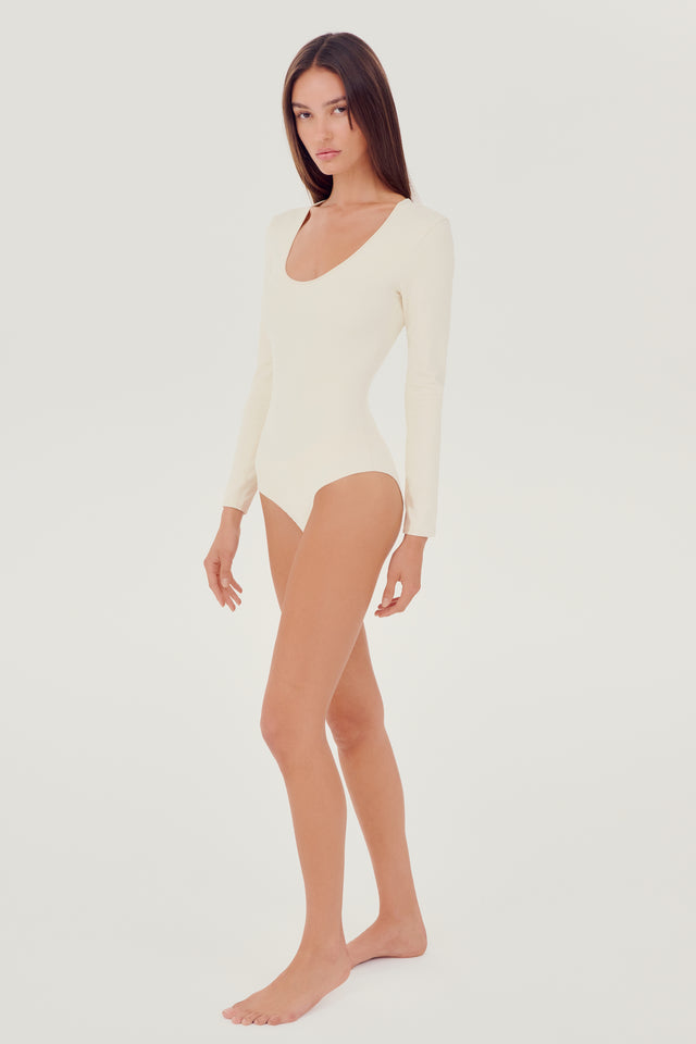Full side view of girl wearing white long sleeve one piece