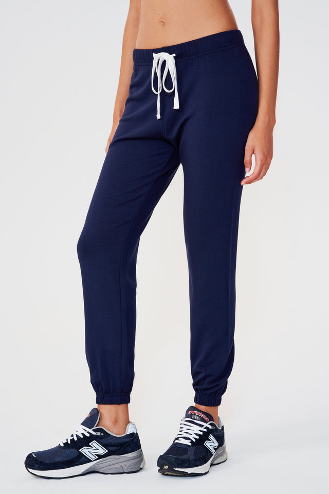 Front view of woman wearing dark blue sweatpant jogger with white drawstring paired with dark blue and white shoes